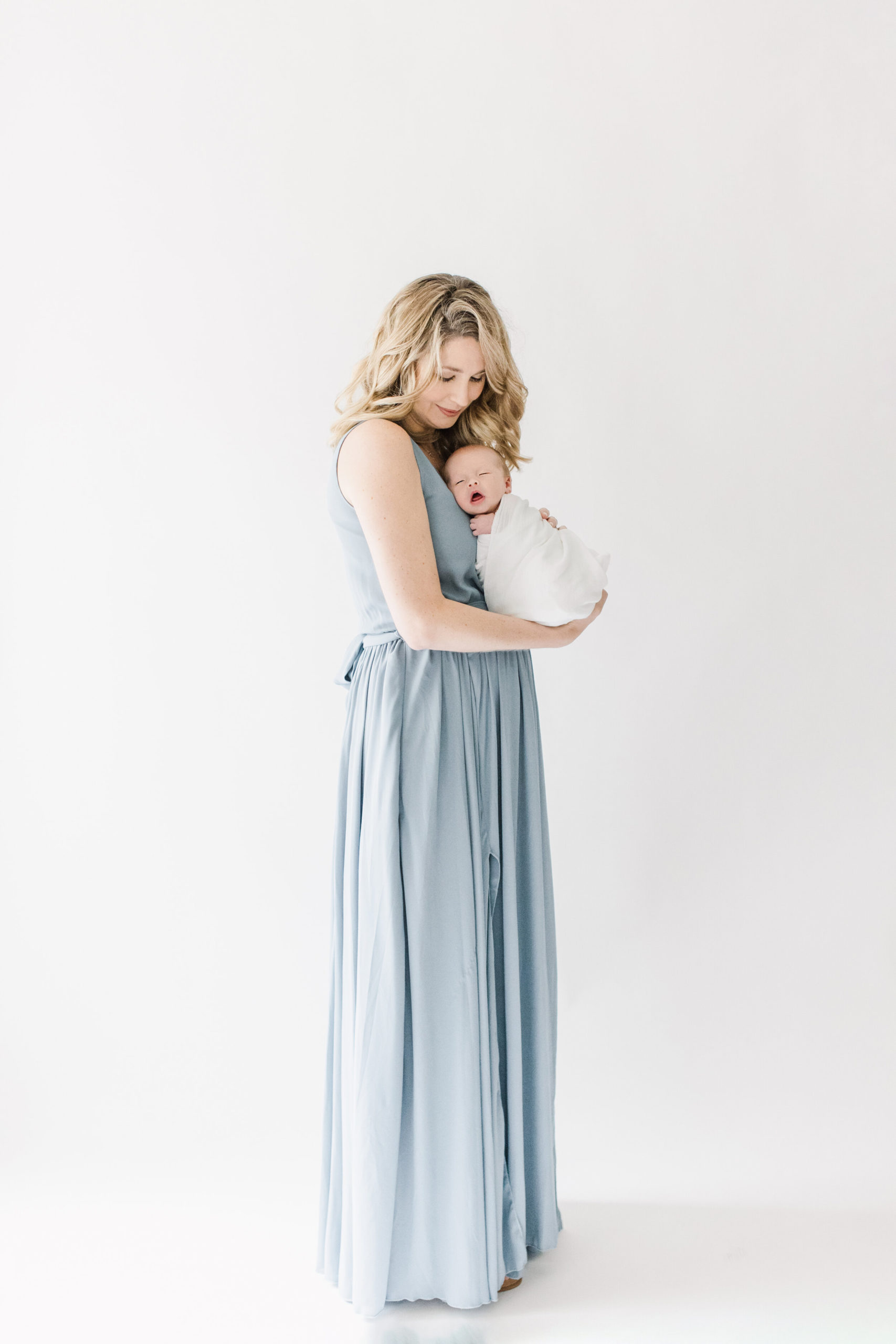 mom in dusty blue dress during newborn portraits