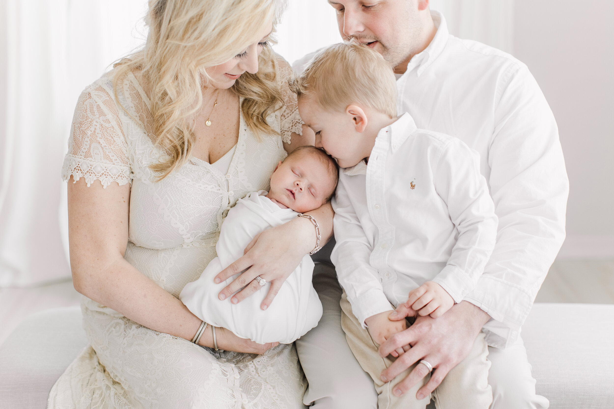 brother kissing baby during newborn photo shoot